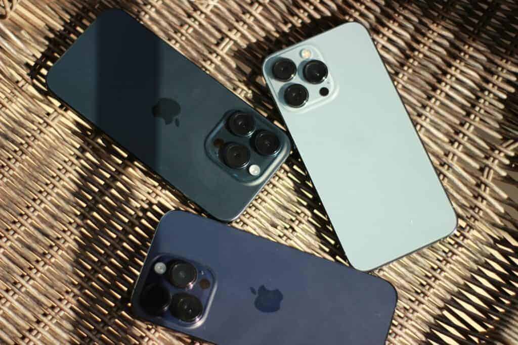 three iphones sitting next to each other on a wicker surface