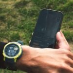 Person checking smartwatch and smartphone outdoors