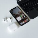 an iphone, ear buds, and laptop on a table