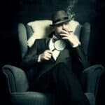 a man sitting in a chair smoking a cigarette