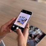 Hands holding phone taking picture of photos