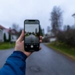 person holding black iphone 5 taking photo of road during daytime
