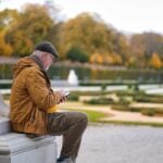 a man sitting on a bench looking at his phone