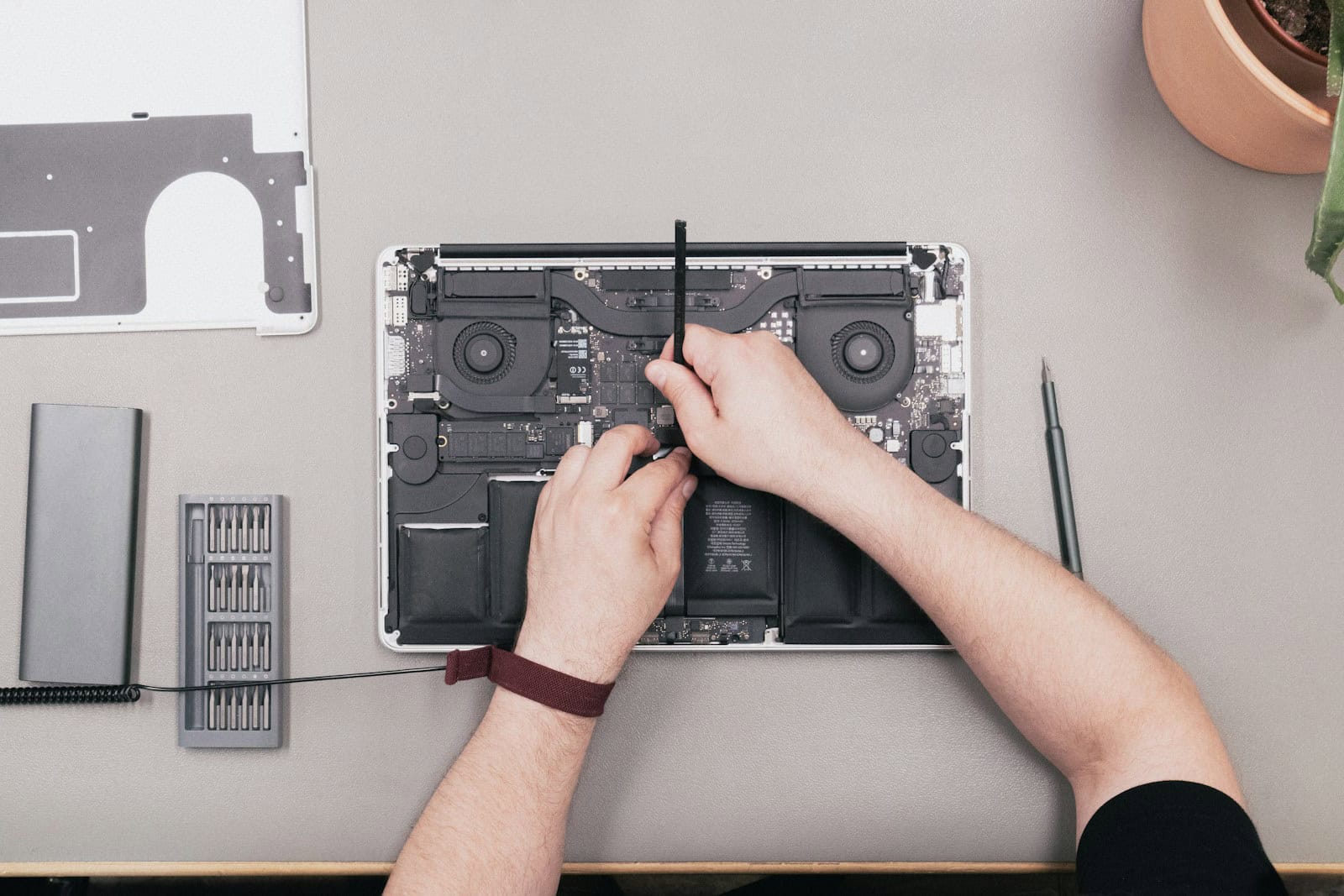 a man is working on a laptop with a screwdriver