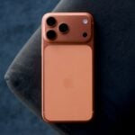 Rose gold smartphone resting on a dark blue surface.