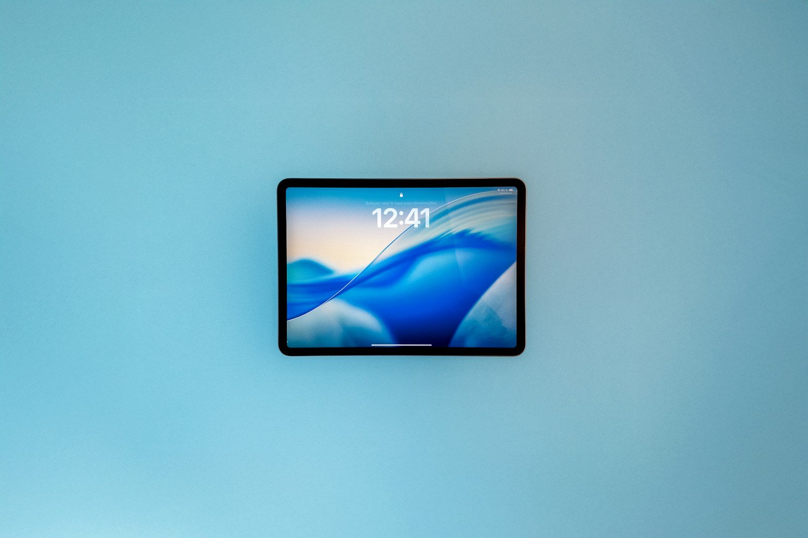 A tablet displaying a blue abstract wallpaper.