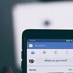 person holding smartphone using facebook account