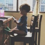 boy holding smartphone while sitting on the chair
