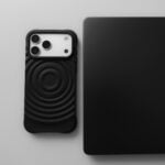 Black smartphone next to a black laptop.