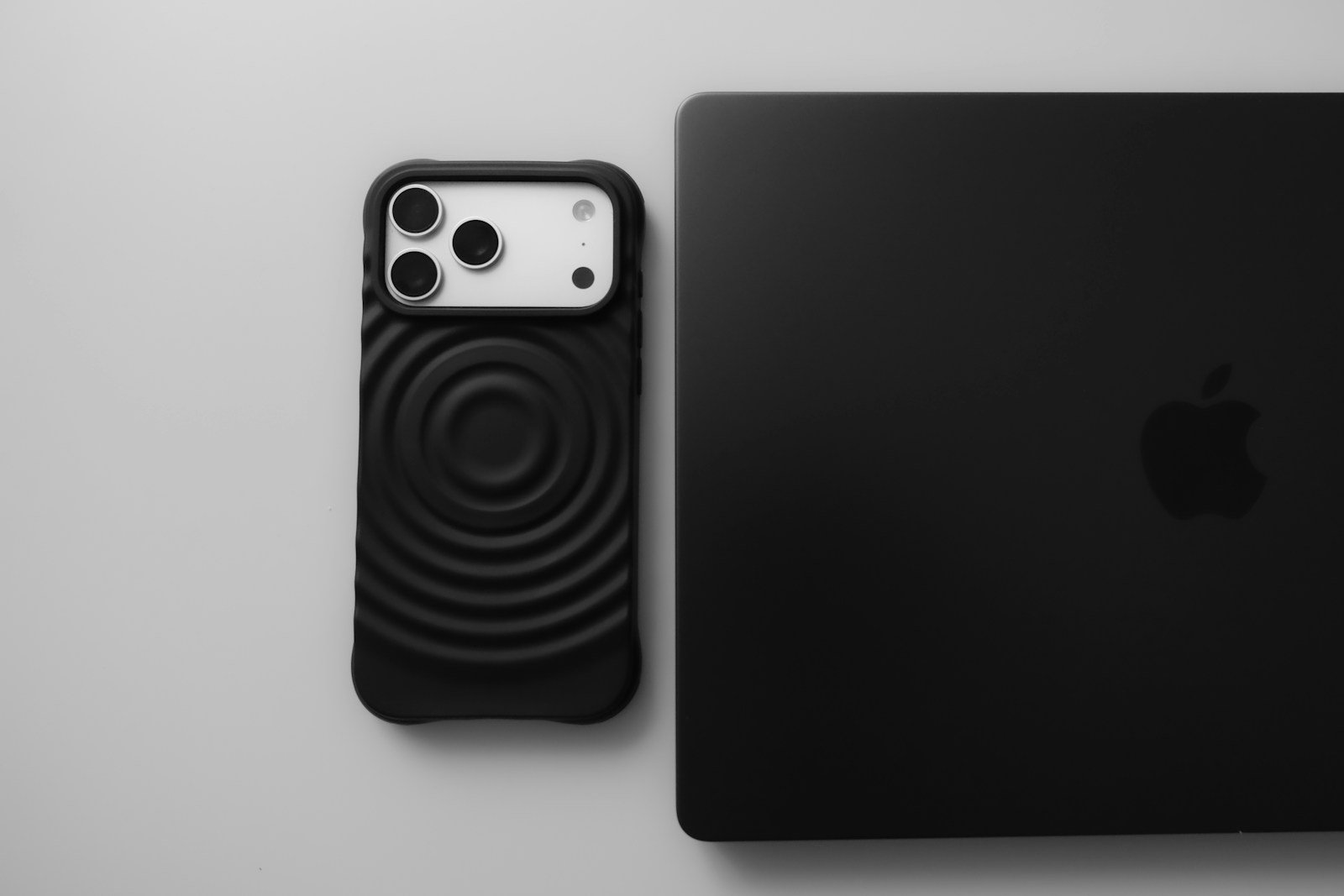 Black smartphone next to a black laptop.