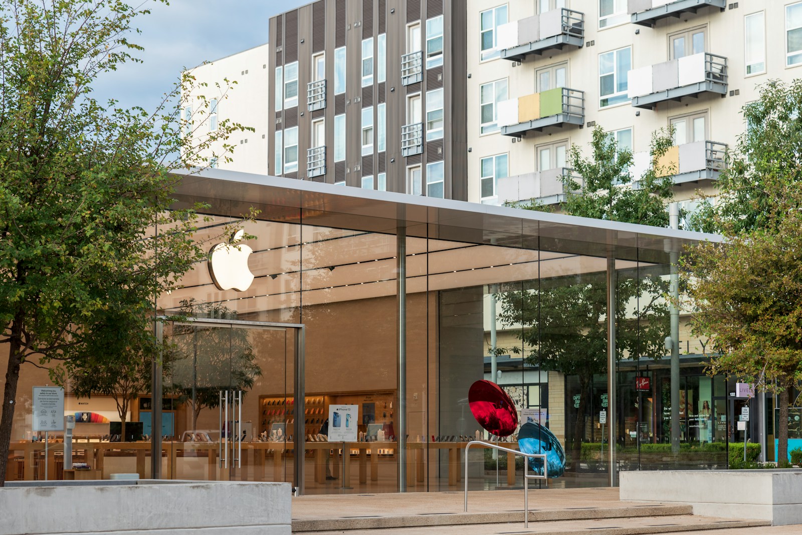 an apple store with a sculpture in front of it