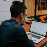 a man sitting at a table using a laptop computer