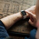 person wearing silver Apple Watch with white band